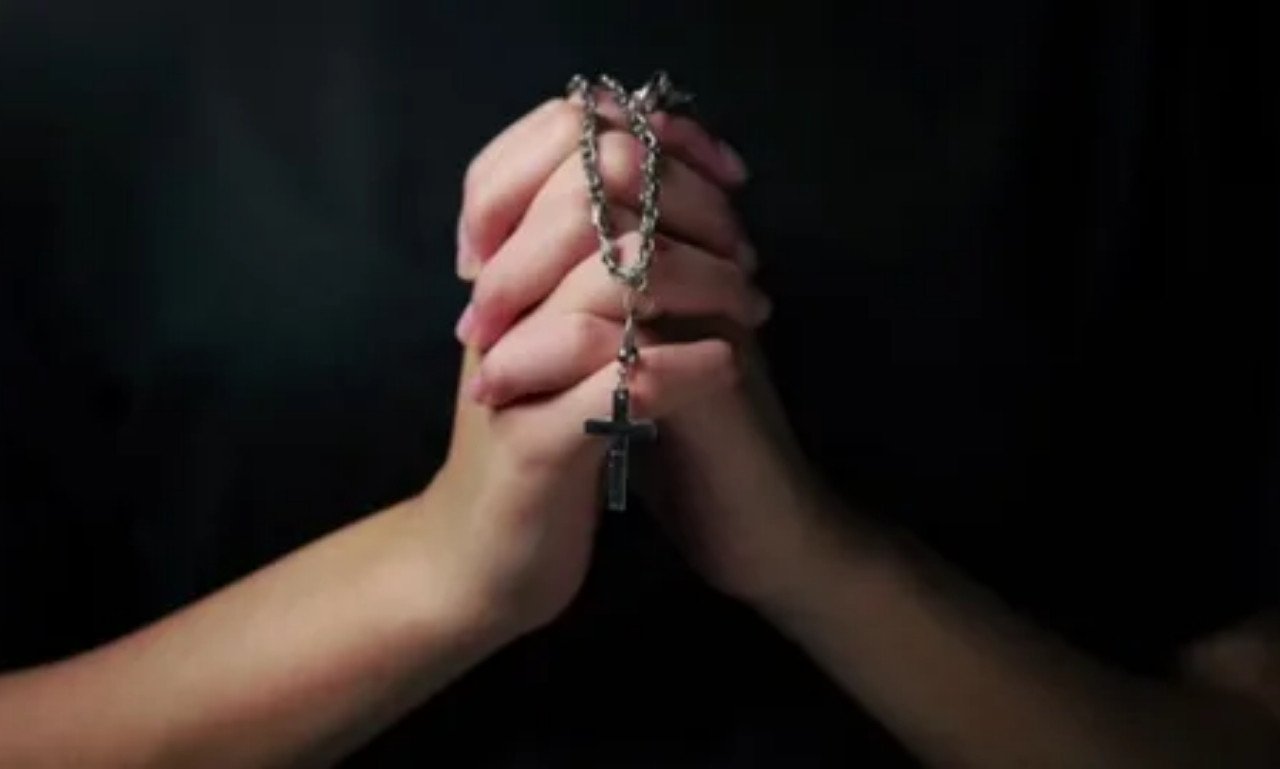 Open Bible with a glowing cross and praying hands symbolizing a powerful prayer for vocations, God's calling, faith, guidance, and spiritual discernment.