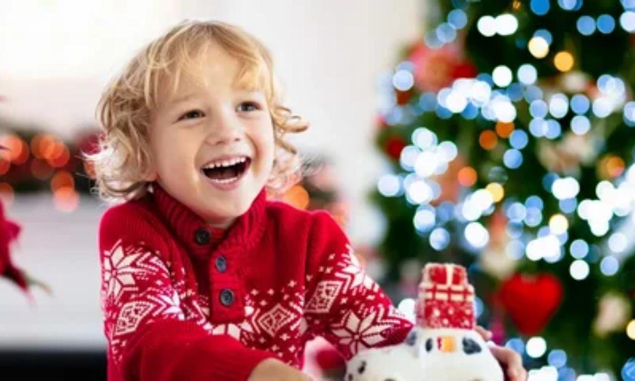 Smiling children opening faith-centered Christmas gifts near a decorated Christmas tree, including children's Bibles, prayer journals, and meaningful Christian presents celebrating the true spirit of Christmas.